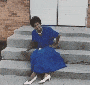 a woman in a blue dress is sitting on a set of stairs .