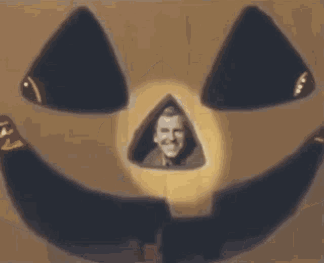 a man is looking out of a pumpkin with a light shining on his face .
