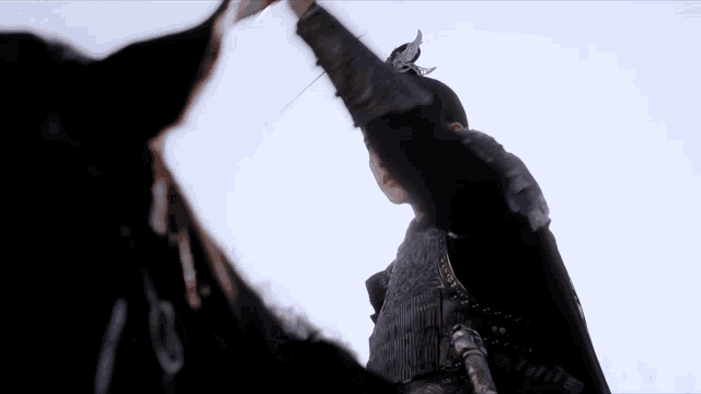 a man in a black armor is holding a sword in his hand