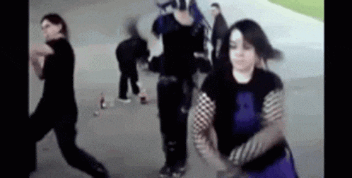 a group of people are dancing in a park . one of the girls is wearing a purple skirt .
