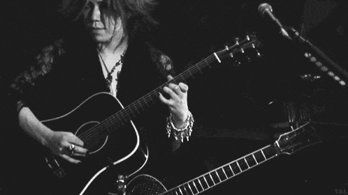 a black and white photo of a woman playing a guitar