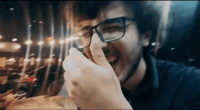 a man wearing glasses is eating a sandwich at night