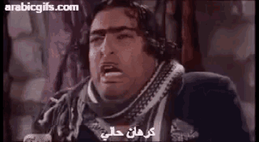 a man wearing headphones and a scarf is making a funny face in arabic .