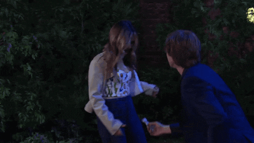 a man in a suit and a woman in a trench coat are hugging each other .