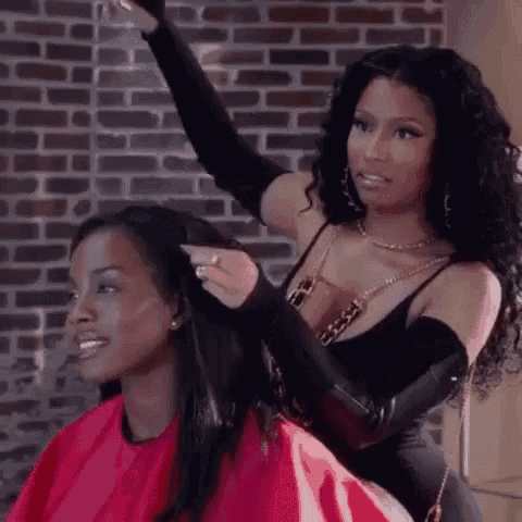 a woman is getting her hair cut by a woman in a red cape .