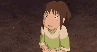 a girl in a green and white shirt is standing in the dirt and looking at the camera .