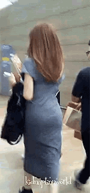 the back of a woman in a blue dress is shown .