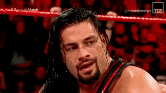 a man with a beard is standing in a wrestling ring .