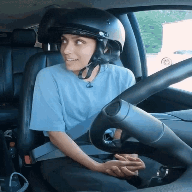 a woman wearing a helmet sits in a car