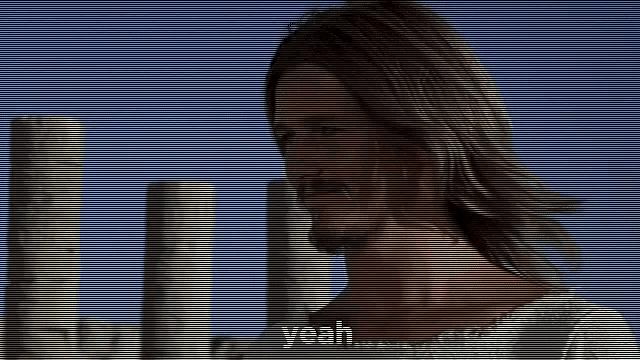 a man with long hair and a beard is standing in front of a group of columns and says yeah .