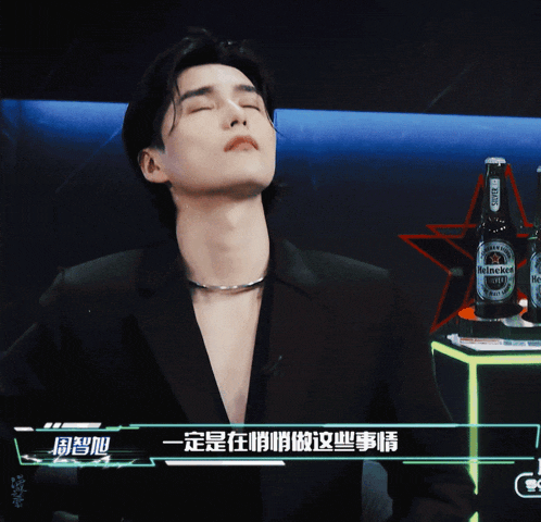 a man with his eyes closed and a bottle of heineken in the background