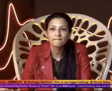 a woman in a red jacket is sitting in a chair on a news channel