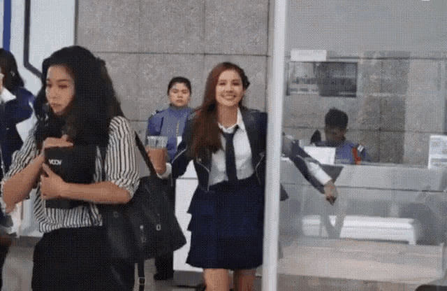 a woman in a school uniform is walking through a metal detector .