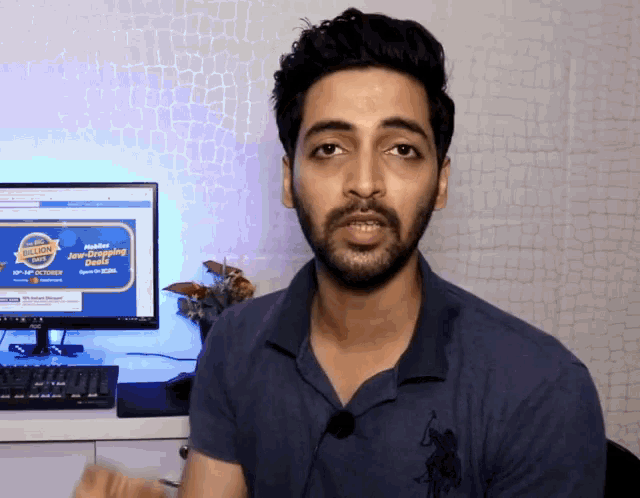 a man in a blue polo shirt is talking in front of a computer screen that says ' jio-dropping ' on it