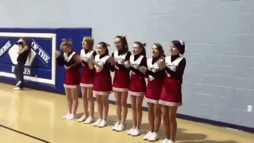 a group of cheerleaders standing in front of a sign that says gems