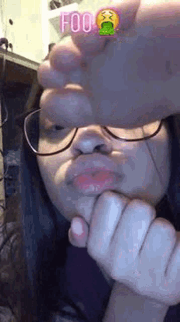 a girl wearing glasses is making a funny face with her hands .