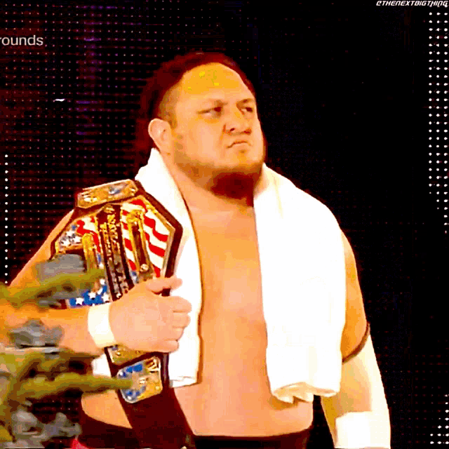 a man with a towel around his neck holds a wrestling belt