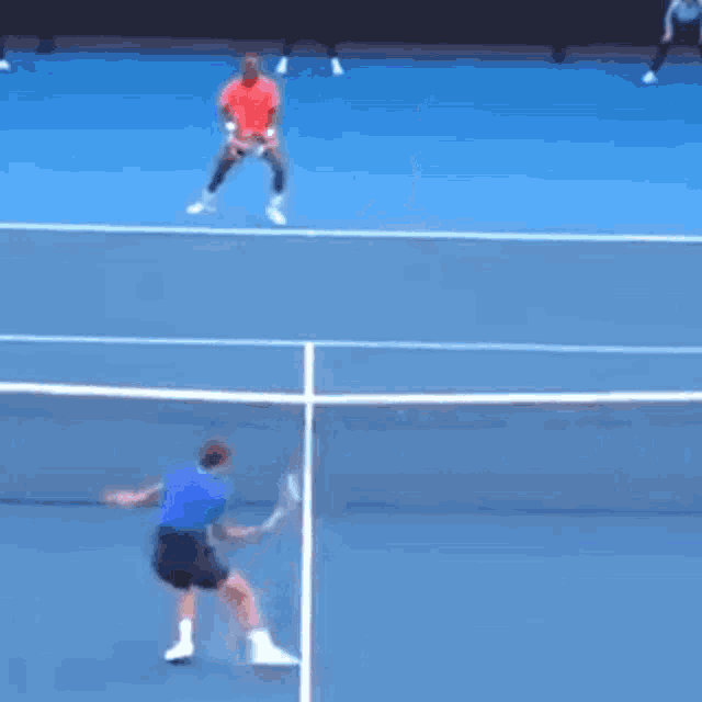 a man in a blue shirt is swinging a tennis racquet