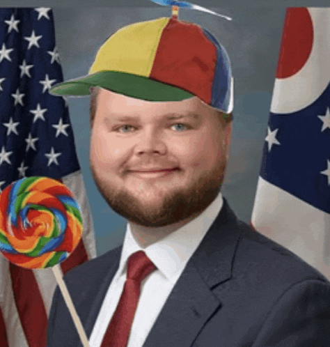 a man in a suit and tie is holding a lollipop and wearing a colorful hat