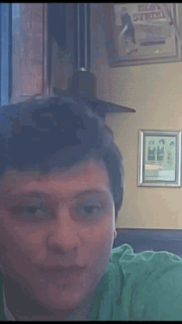 a man in a green shirt is sitting in front of a wall with a picture on it that says ' texas steel '