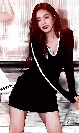 a woman in a black dress is standing on a stage and dancing .