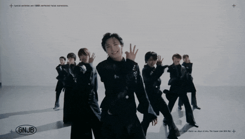 a group of young men are dancing in front of a white wall with gnjb written on the bottom