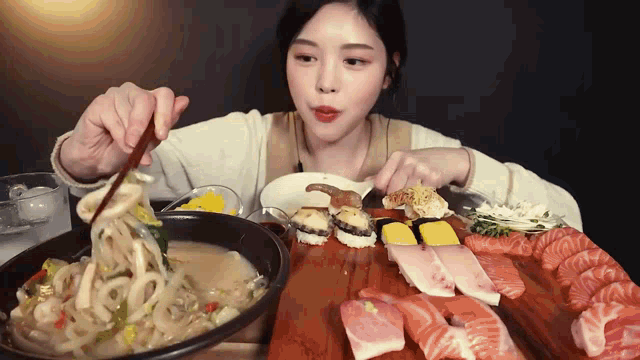 a woman is eating noodles and sushi on a table