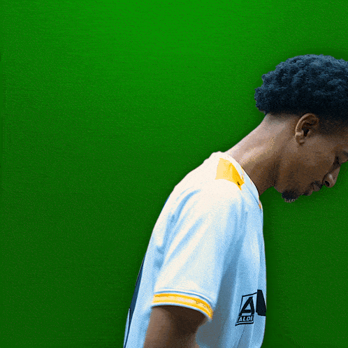 a man wearing a white yasha 94 jersey stands in front of a green background