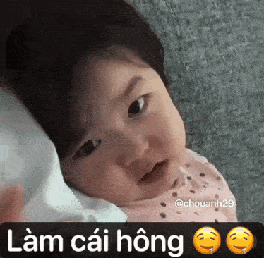 a baby is laying on a pillow with the words " lam cai hong " written on the bottom