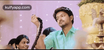 a man in a green shirt is holding a woman 's hair .