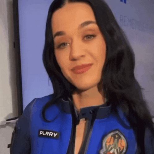 a close up of a woman wearing a blue jacket with the name perry on it
