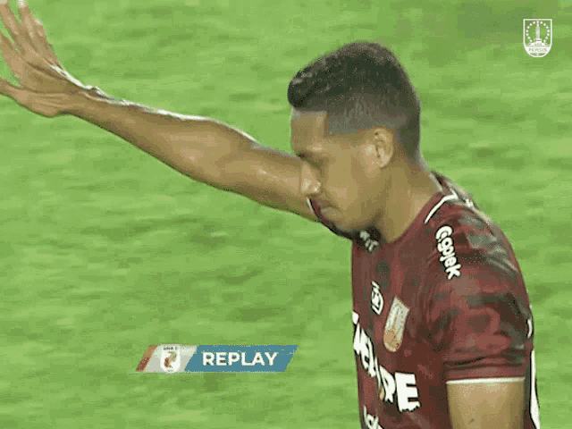 a soccer player in a red jersey with the word replay on it