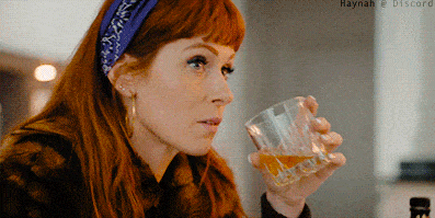 a woman with red hair is drinking from a glass with haynah @ discord written in the corner