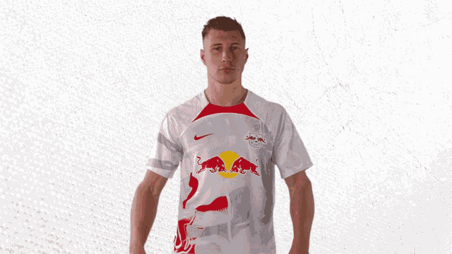 a man wearing a white shirt with red bulls on it is giving a thumbs up