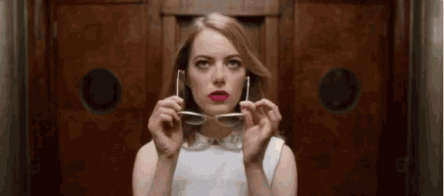 a woman is holding a pair of sunglasses in her hands .