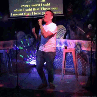 a man singing into a microphone with a screen behind him that says every word i said