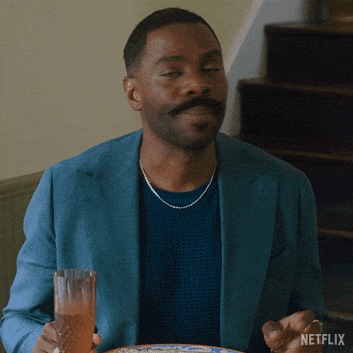 a man in a blue jacket is holding a glass with netflix written on the bottom right