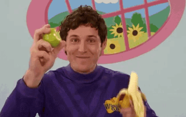 a man is holding a green apple and a banana .