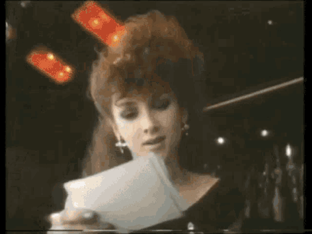 a woman in a black dress is holding a piece of paper
