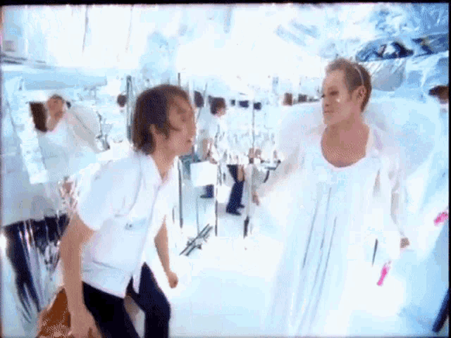a man in a white shirt is standing next to a woman in a white dress with wings