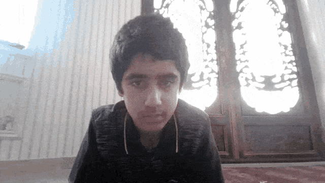 a young boy looking at the camera in front of a door