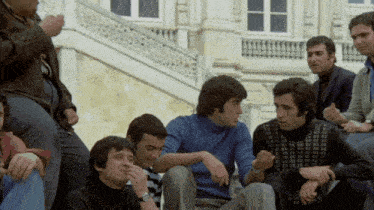 a group of men are sitting on a set of stairs talking