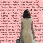 a woman in a white dress is standing in front of a wall of words including selena gomez fetish and gucci mane
