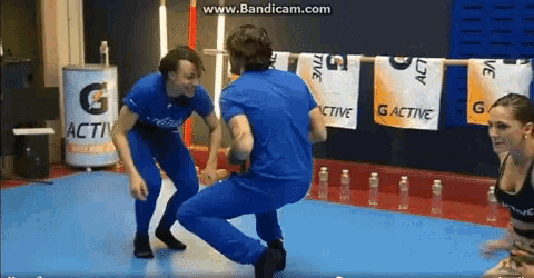 a man in a blue shirt is squatting down in front of a sign that says g active