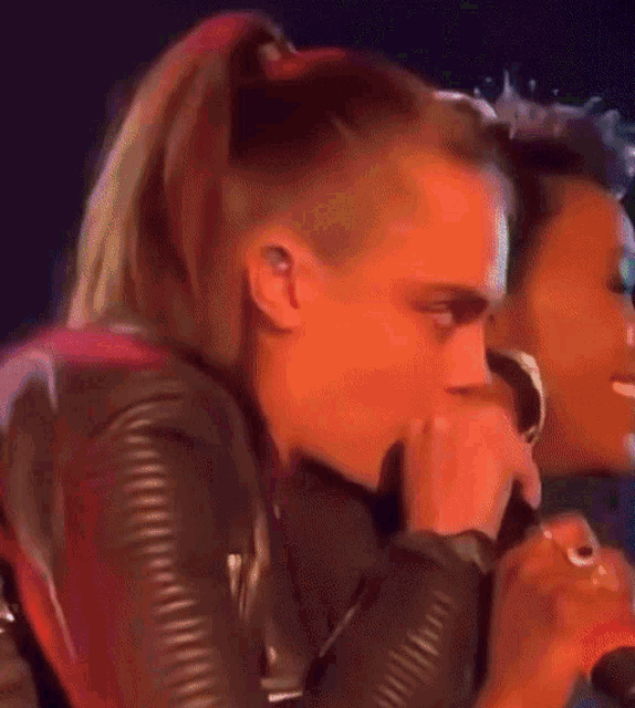 a woman with a ponytail is singing into a microphone while another woman looks on