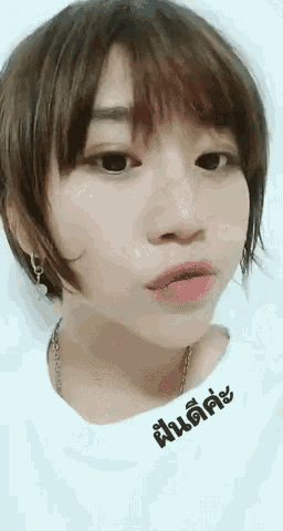 a girl with short hair is wearing a white shirt with a foreign language on it .