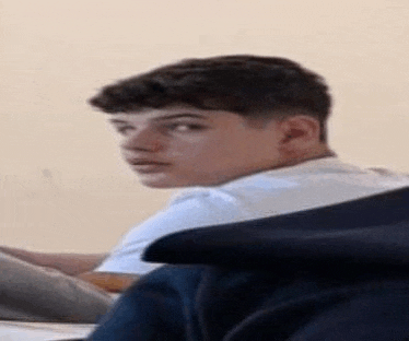 a young man is sitting on a couch looking at something .