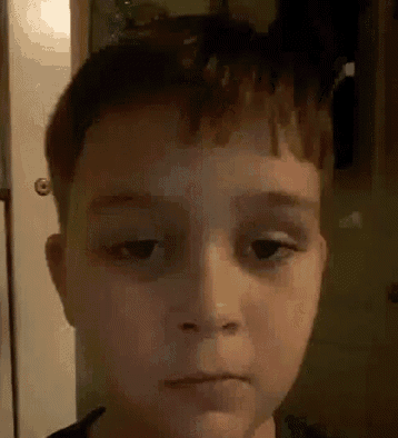 a close up of a young boy 's face with a serious look on his face .