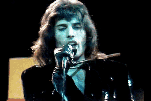 a man singing into a microphone with long hair