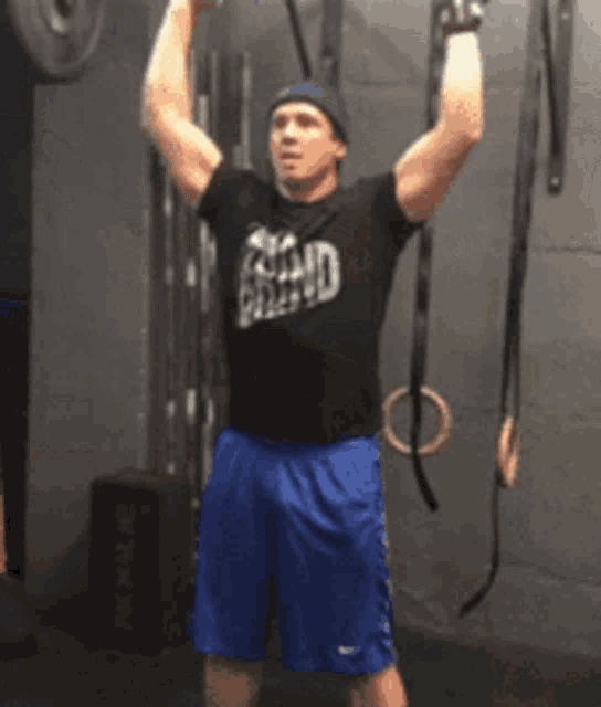 a man in a black shirt with the word grand on it is lifting a barbell over his head